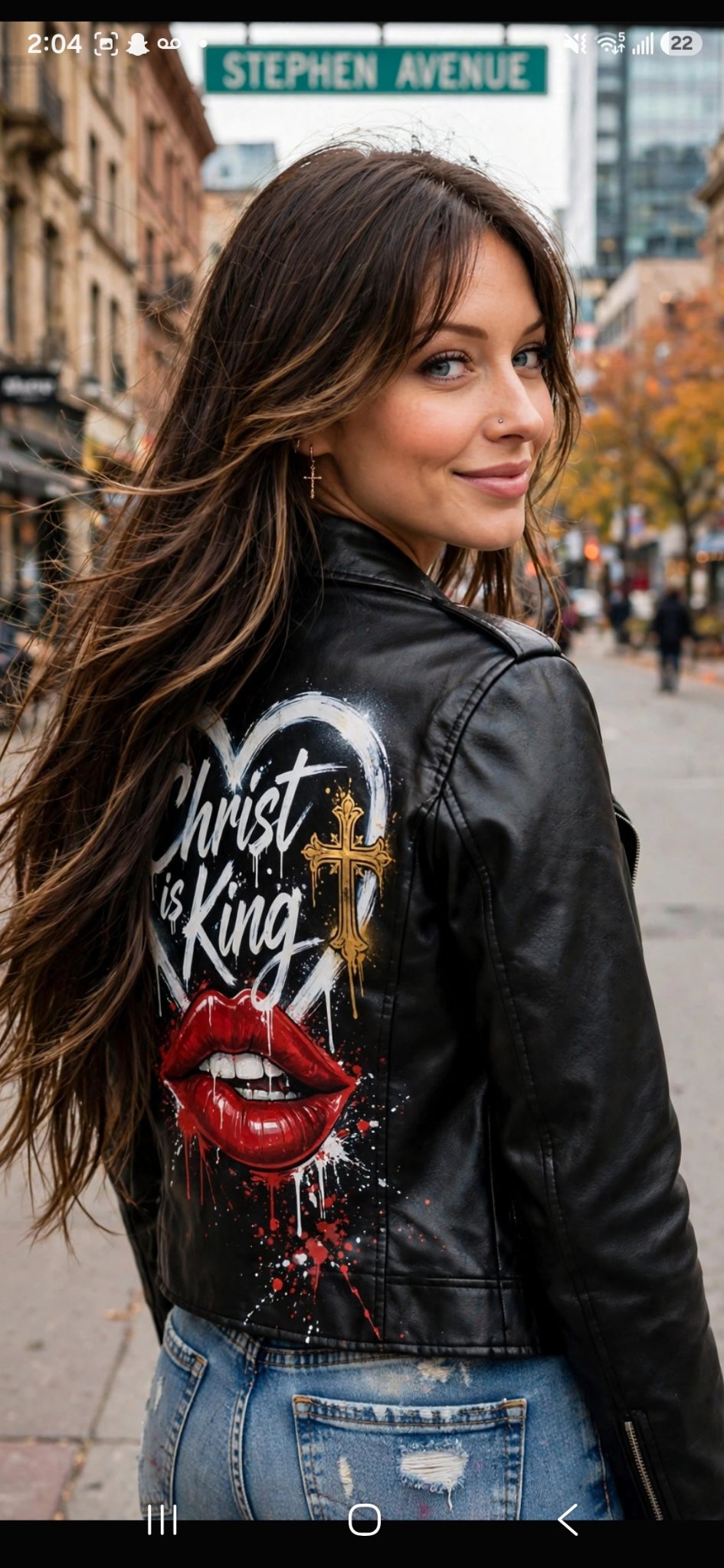 Jelah looking back over her shoulder on Stephen Avenue, wearing a black jacket with the Christ Is King lip art across the back